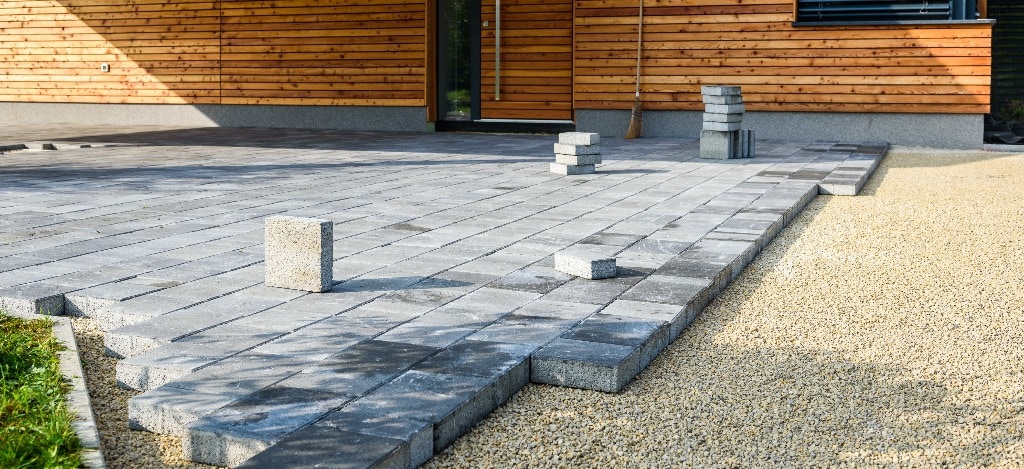 Laying gray concrete paving slabs in house courtyard driveway patio.